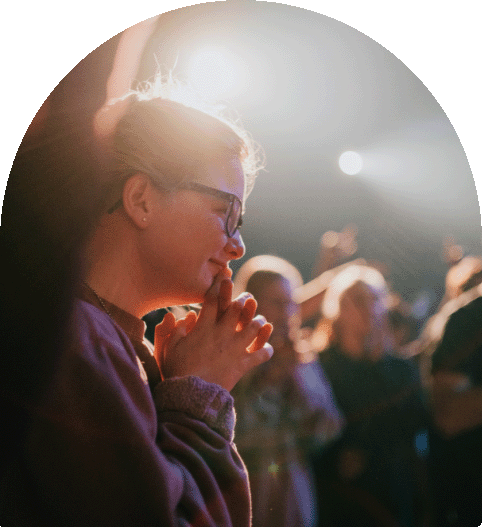 An image of a woman smiling with closed hands in prayer