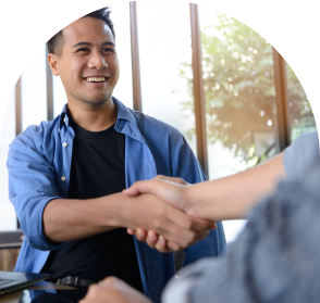 An image of a man in front of a window shaing hands with someone else