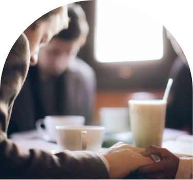 A group of people at a cafe praying together with coffee on the table