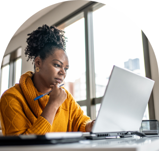 A woman holding a pen and looking at her laptop.