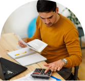 A photo of payroll processor using a calculator in front of a laptop screen with some papers in his hand.