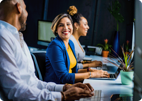 A group of people smiling in front of laptops